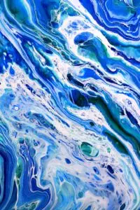 Dynamic abstract fluid art with vibrant blue and white swirls, evoking ocean waves.